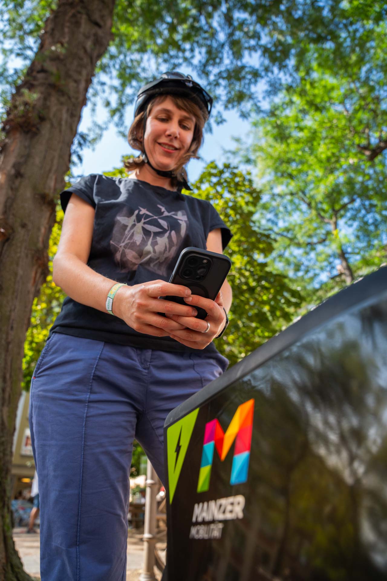Foto einer Frau, die mit dem Smartphone am Fahrrad ist