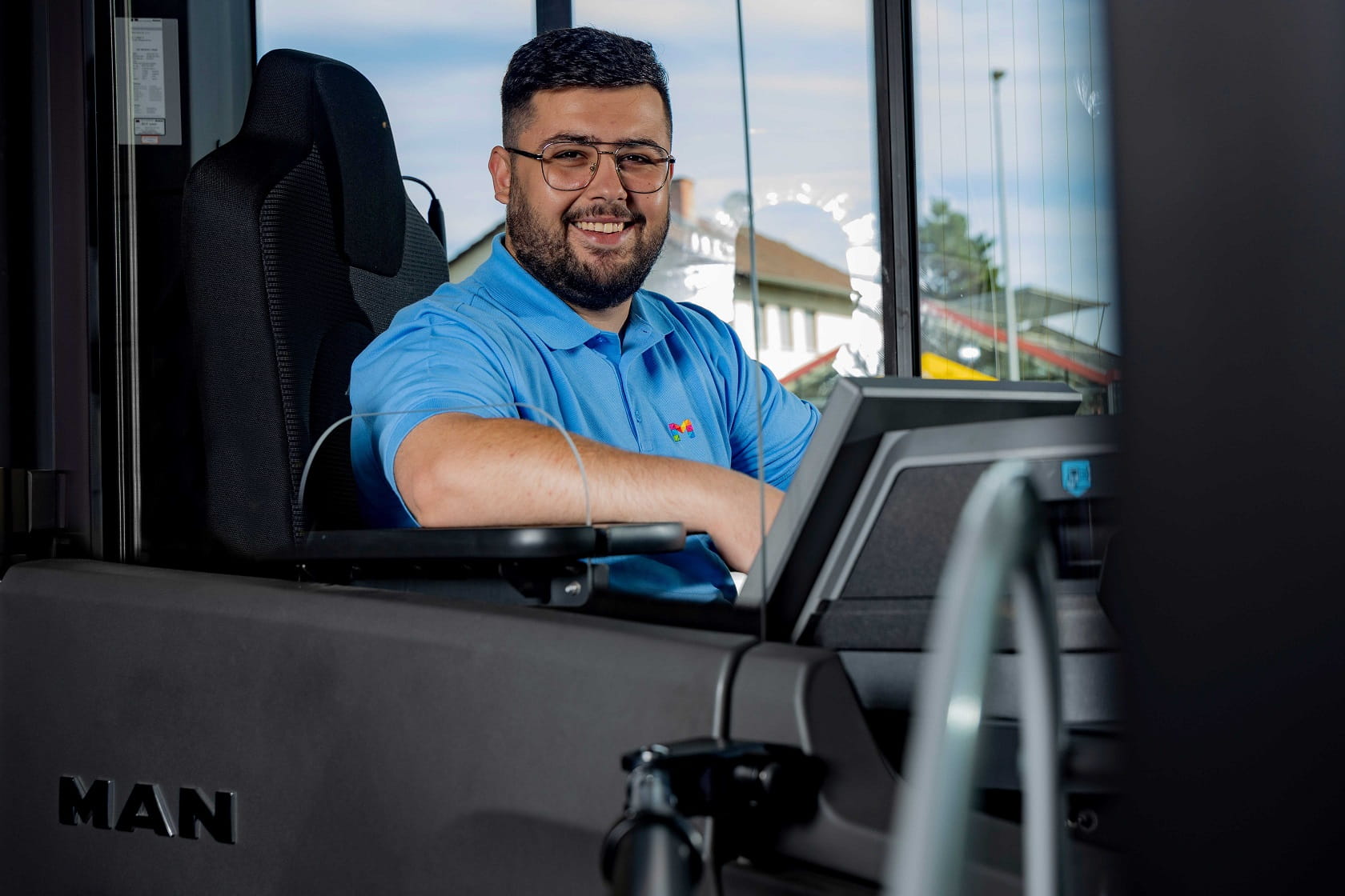 Busfahrer sitzt auf seinem Platz mit Blick zur Kamera. 