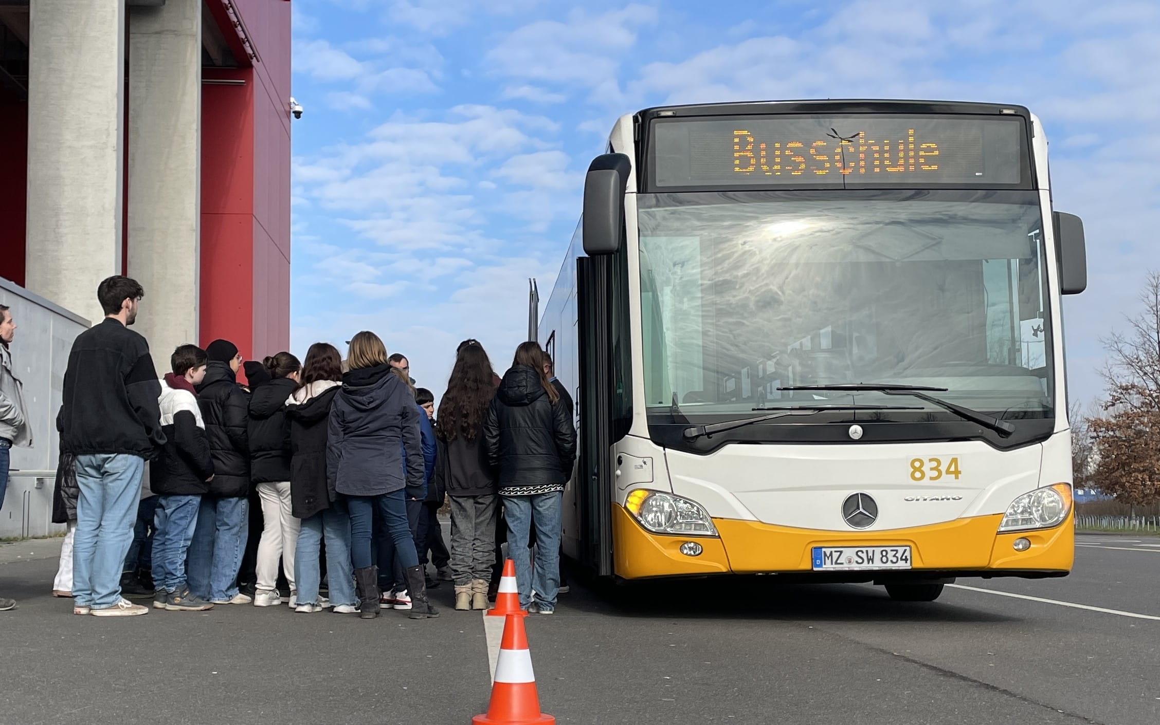 Bus vor der Arena mit einer Schlange von einsteigenden Kindern vor der Tür